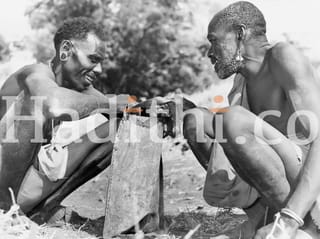 Tribes Men fastening a bag.